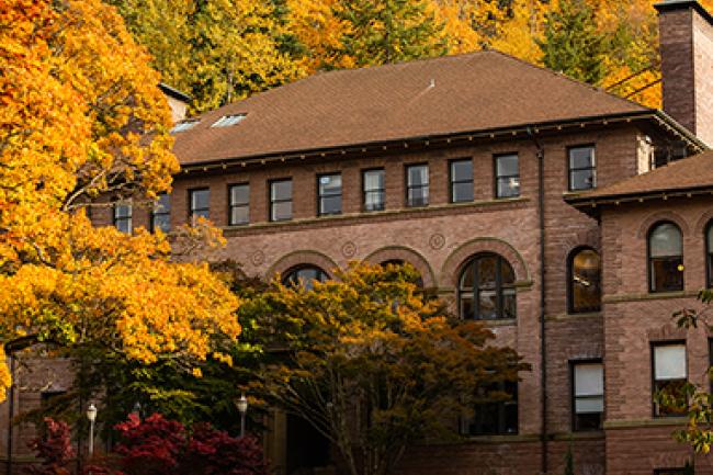 Brick academic building surrounded by fall foliage