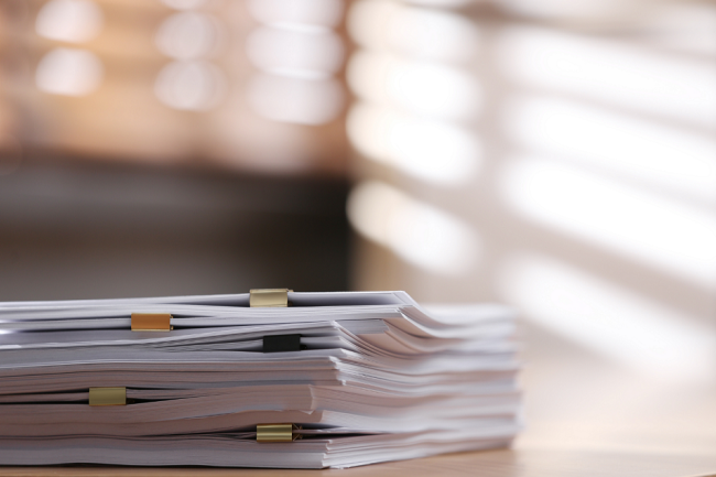 a neat pile of papers sits on a desk in an office